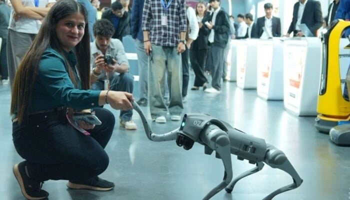 A woman shakes hand with robotic dog presented by Galgotias University. — X@GalgotiasGU