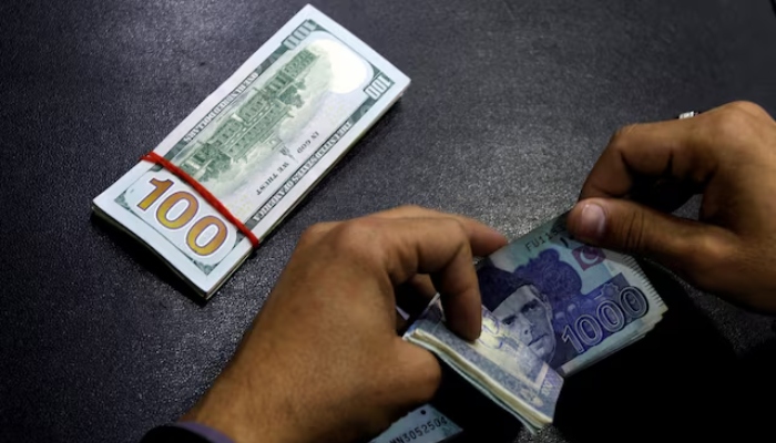 A currency trader counts Pakistani Rupee notes as he prepares an exchange of US dollars in Islamabad. — Reuters/File