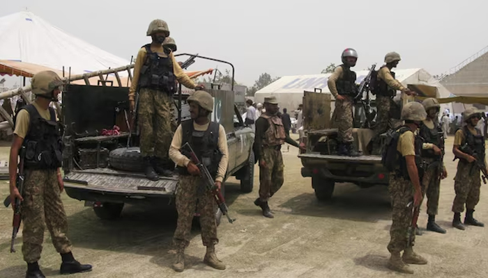 Pakistan Army soldiers stand guard as people, who fled the military offensive against militants in North Waziristan, receive food supply from the army in Bannu, in Khyber-Pakhtunkhwa, July 2, 2014. — ISPR