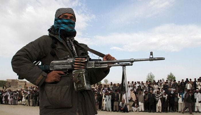 A member of the Taliban insurgent and other people stand at the site during the execution of three men in Ghazni Province April 18, 2015. — Reuters