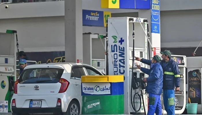 Employees at a fuel station attend to their customers in Islamabad. — AFP/File