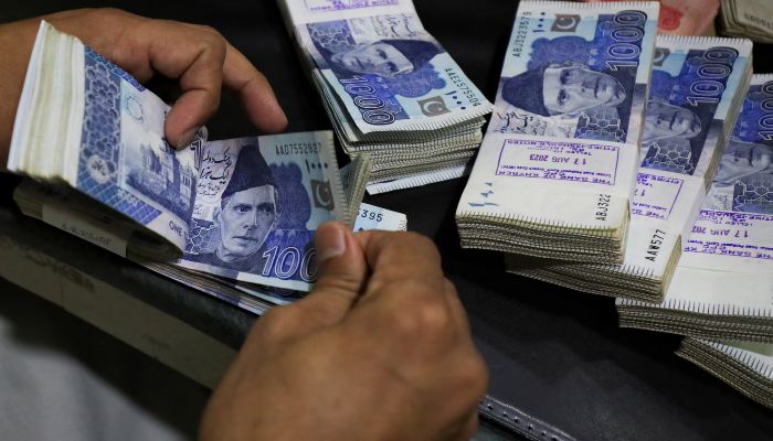 An employee counts Pakistani rupee notes at a bank in Peshawar, August 22, 2023. — Reuters