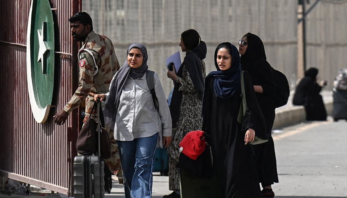 Pakistani nationals walk across the Taftan border after returning from Iran, in Balochistan province, on March 2, 2026 amid ongoing US-Israel strikes on Iran. — AFP