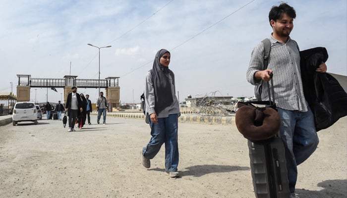 Pakistani nationals walk across the Taftan border after returning from Iran, in Balochistan province, on March 2, 2026 amid ongoing US-Israel strikes on Iran. — AFP