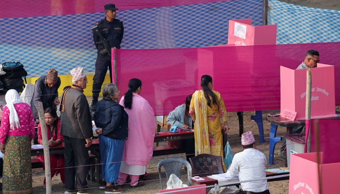 People queue to vote as a member of the Nepal police stands guard at a polling station during the general election in Damak, Jhapa district, Nepal, March 5, 2026. — Reuters