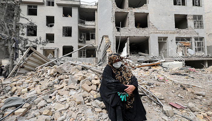 A woman sits outside her destroyed apartment after it was damaged by an airstrike while she was inside, amid the US.-Israeli conflict with Iran, in Tehran, Iran on March 12, 2026. — Reuters