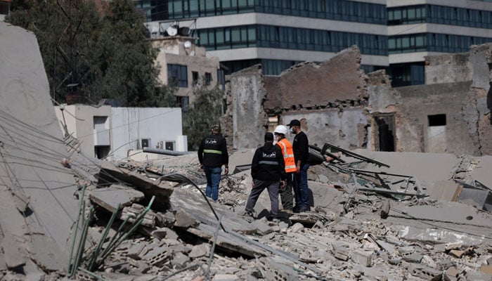 People stand amidst debris at the site of an Israeli strike, following an escalation between Hezbollah and Israel amid the US-Israeli conflict with Iran, Zuqaq al-Blat district in central Beirut, Lebanon, March 18, 2026.— Reuters