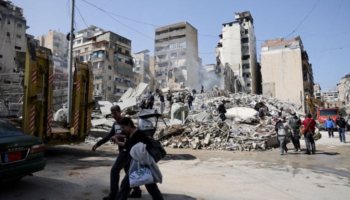 People walk near debris at the site of an Israeli strike, following an escalation between Hezbollah and Israel amid the US-Israeli conflict with Iran, Zuqaq al-Blat district of central Beirut, Lebanon, March 18, 2026. — Reuters