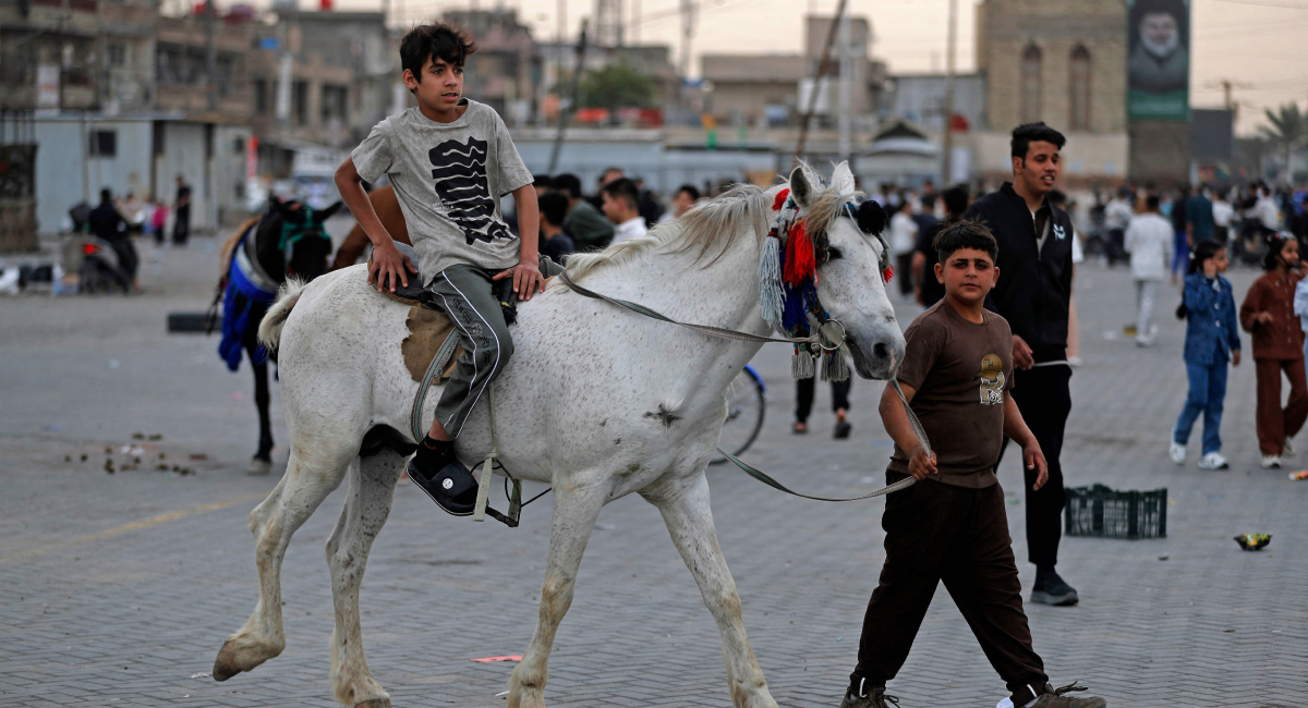 A boy reacts while riding a horse at an amusement park on Eid ul Fitr, which marks the end of the Muslim holy fasting month of Ramadan, in the eastern Sadr City, suburb of Baghdad on March 21, 2026. — AFP