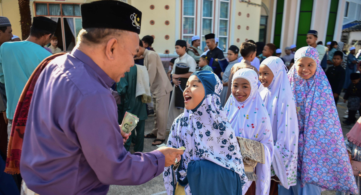 A man distributes Eidi to children following Eid ul Fitr prayers, which marks the end of the holy fasting month of Ramadan, at a mosque in the southern Thai province of Narathiwat on March 21, 2026. — AFP