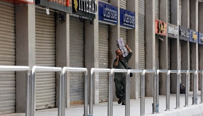 A man walks past closed market during a partial lockdown after Sindh provincial government decided to shut markets, restaurants, public beaches and discouraged large gatherings to curb the outbreak of the coronavirus disease (Covid-19), in Karachi, Pakistan July 30, 2021. — Reuters