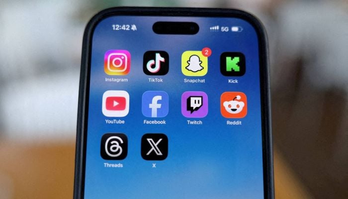 Instagram, TikTok, Snapchat, Kick, YouTube, Facebook, Twitch, Reddit, Threads, and X applications are displayed on a mobile phone in this picture illustration taken on December 9, 2025. — Reuters