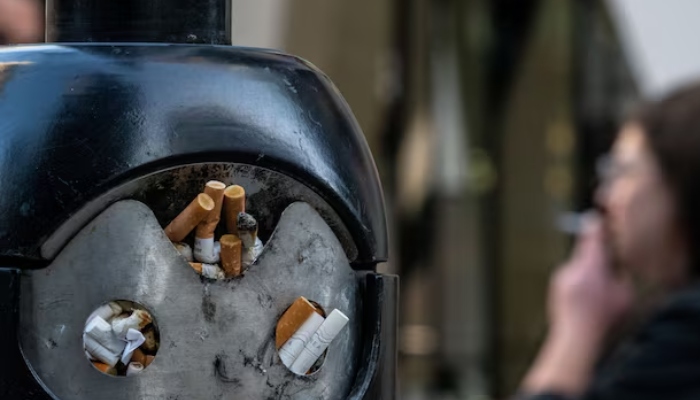 A smoker stands next to a bin for cigarette butts in London, Britain, November 26, 2024. — Reuters