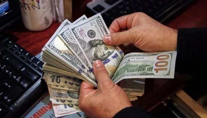 A moneychanger counts $100 banknotes at an exchange company. — Reuters/File