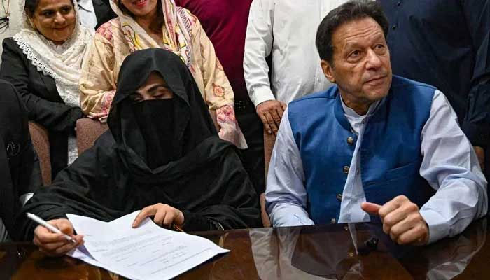 Former prime minister Imran Khan (right), along with his wife Bushra Bibi, signs surety bonds for bail in various cases, at the registrars office in the Lahore High Court on July 17, 2023. — AFP
