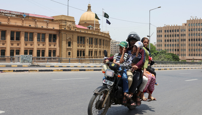 Boys wear caps to shield themselves from the sun as they ride with family on a motorbike amid hot and humid weather, near the Karachi Port Trust building, in Karachi on May 3, 2026. — Reuters