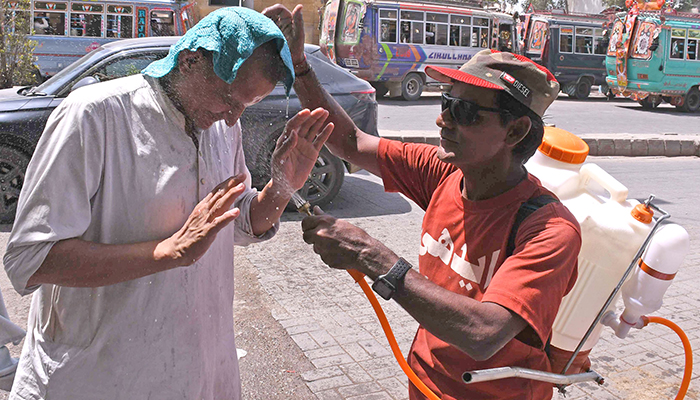An NGO volunteer sprays water on a passerby to cool him off on a hot summer day in Karachi, on May 4, 2026. — Online