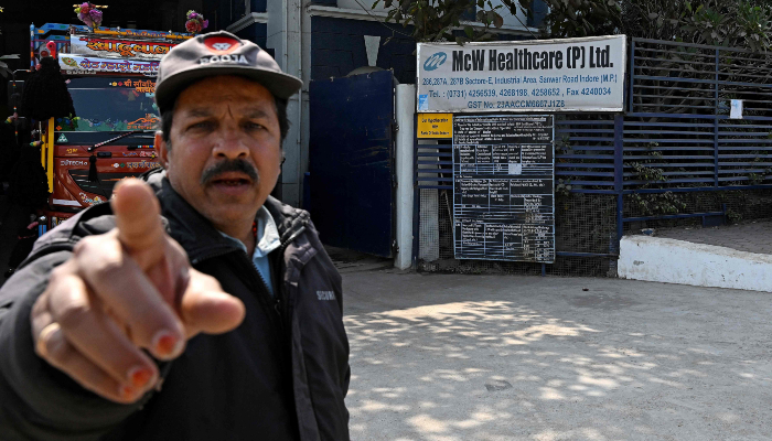 This photograph, taken on January 19, 2026, shows a security guard pointing to a camera outside Indian pharmaceutical firm McW Healthcare´s manufacturing plant in Indore, India. — AFP