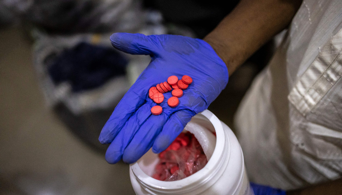 An officer holds seized red Tapentadol tablets at the National Drug Law Enforcement Agency (NDLEA) facility in Lagos, on February 19, 2026. — AFP