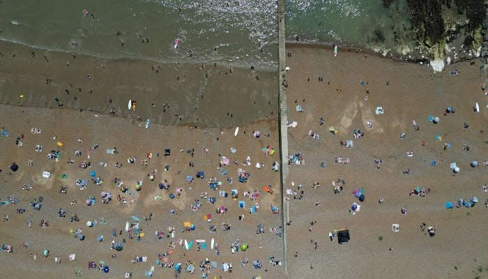 An aerial picture shows people relaxing in the sunshine on Saltdan beach, east of Brighton, on the south coast of England, on May 25, 2026, with heatwave conditions spreading to parts of southeast England and London. — AFP