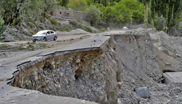 A vehicle drives past a partially collapsed section of the Karakoram Highway damaged after a lake outburst near Hassanabad village of Gilgit-Baltistan region. — AFP/File