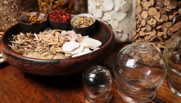 Close-up of herbal ingredients and glass jars used in traditional Chinese medicine therapy. — Pexels