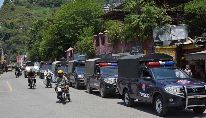 Commuters ride past security personnel as they patrol a street ahead of a protest by the banned Joint Awami Action Committee (JAAC) in Muzaffarabad, Azad Jammu and Kashmir on June 7, 2026. — AFP