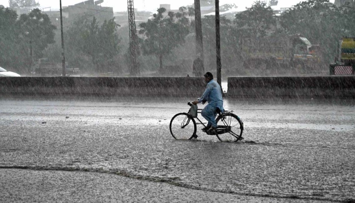 Cyclist pass through water accumulated at IJP Road during heavy rain in Islamabad, June 4, 2026. — APP
