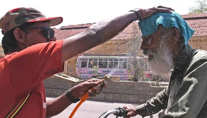 A volunteer sprays water on a passer-by to cool him off at a roadside camp in the metropolis amid scorching heat.— Online