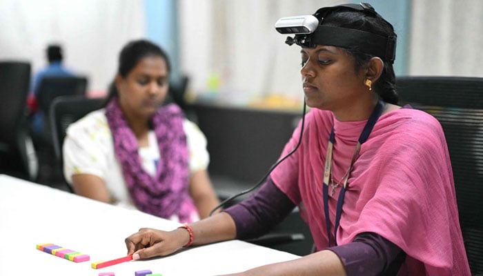 A worker (R) wearing a RGB camera on her head recording actions through motion capture while arranging colored blocks at AI data company Objectways office in Tamil Nadus Karur district.— AFP