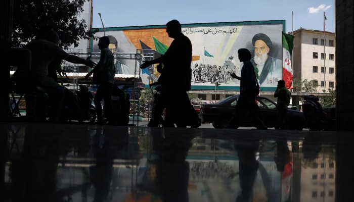 People walk near a mural depicting the late leader of the Islamic Revolution, Ayatollah Ruhollah Khomeini, and Irans late Supreme Leader Ayatollah Ali Khamenei, on a street in Tehran, Iran, June 14, 2026.