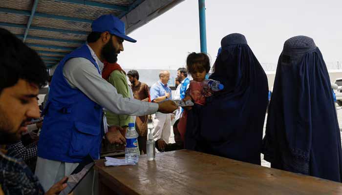 A displaced Afghan woman receives cash aid from an NGO employee at a cash aid distribution centre for displaced people in Kabul, Afghanistan. — Reuters/File