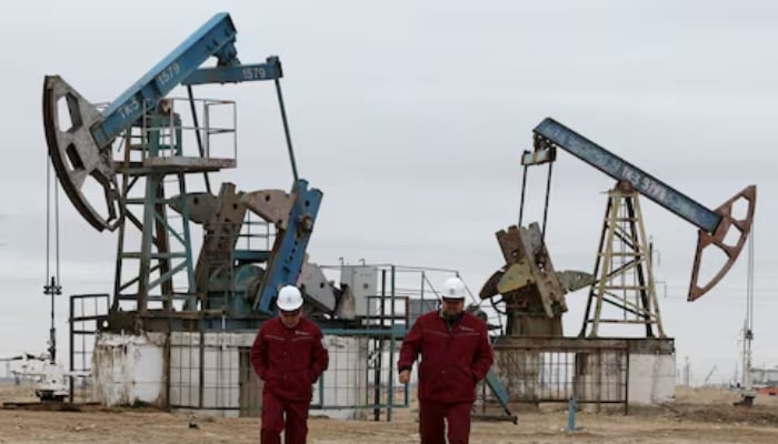 Workers walk as oil pumps are seen in the background in the Uzen oil and gas field in the Mangistau Region of Kazakhstan, November 13, 2021. — Reuters