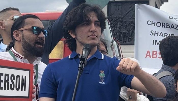 PTI supporter Shayan Ali stands before a mic at an event in the UK. — X/@ShayanA2307