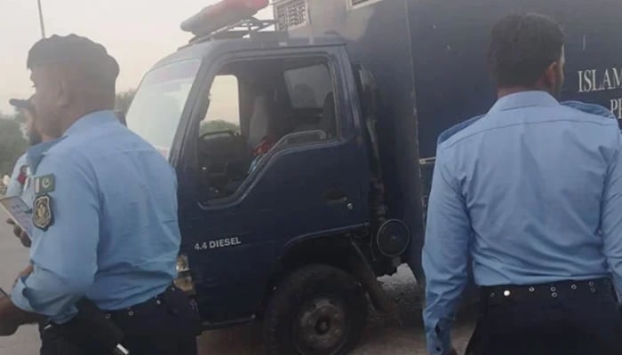 Islamabad police officials standing beside prison van following the armed attack by unidentified assailants at Sangjani Toll Plaza on October 25, 2024. — Geo News