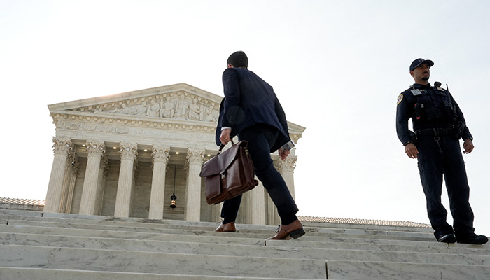 A man walks past a police officer standing in front of the Supreme Court building in Washington, DC, US, June 30, 2026. — Reuters