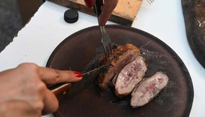 A woman slices beef at a barbecue at her home in Buenos Aires, Argentina June 23, 2024. — Reuters