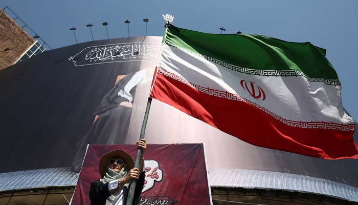 A woman holds an Iranian flag on a street in Tehran, Iran, June 30, 2026. — Reuters