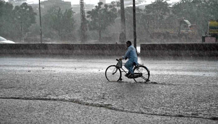 A cyclist passes through water accumulated at IJP Road during heavy rain in Islamabad, June 4, 2026. — APP
