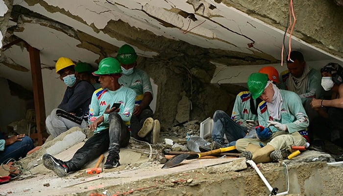 Rescuers take a break beneath a collapsed structure during search and recovery operations in Caraballeda, La Guaira state, Venezuela, on July 11, 2026, following twin earthquakes that struck the region. — AFP