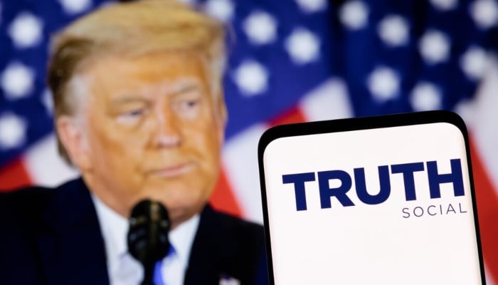 The Truth social network logo is seen on a smartphone in front of a display of former U.S. President Donald Trump in this picture illustration taken February 21, 2022. — Reuters