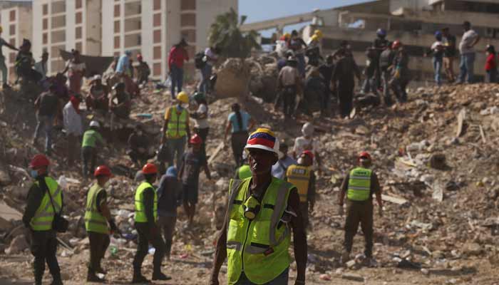 A search and rescue volunteer wearing a Venezuelan flag attached to his helmet searches debris alongside other people, in the aftermath of the June 24 earthquakes, in La Guaira, Venezuela, July 16, 2026.— Reuters