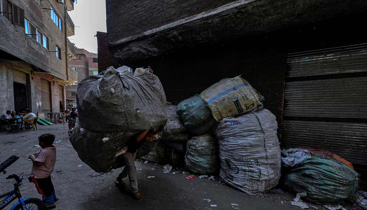 An Egyptian man carries a large bag filled with rubbish at the garbage city in the Manshiyet Nasser neighbourhood in Cairo on July 6, 2026.— AFP