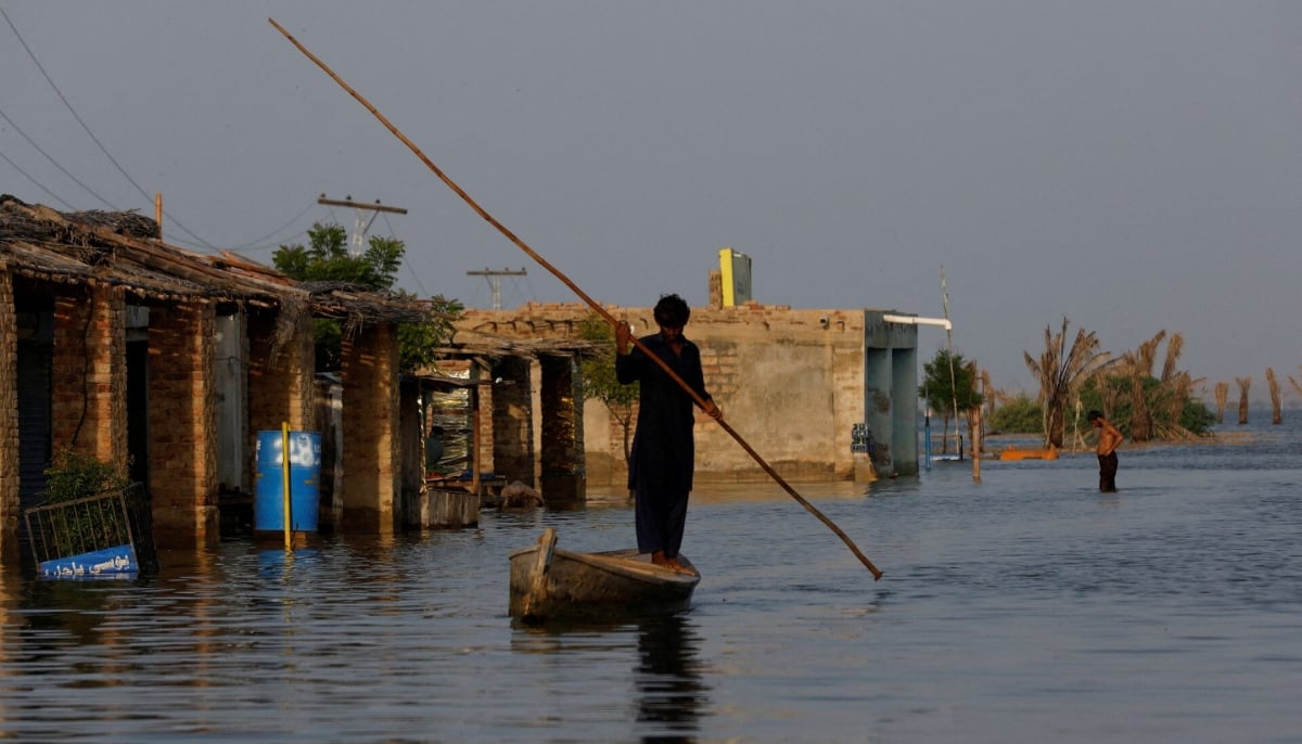 A man rows his boat as he passes through flooded market, following rains and floods during the monsoon season in Bajara village, at the banks of Manchar lake, in Sehwan on September 6, 2022. — Reuters