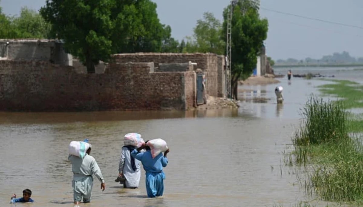 Flood affectees can be seen walking into floodwater in Sindh after devastating floods. — AFP/File