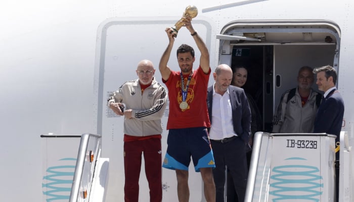 Spains coach Luis de la Fuente (left), Spains midfielder Rodri (centre) and President of the Spanish Football Federation Rafael Louzan (third from left) pose with their trophy upon their arrival from the US after winning the 2026 World Cup, in Madrid Barajas airport, on July 20, 2026. — AFP