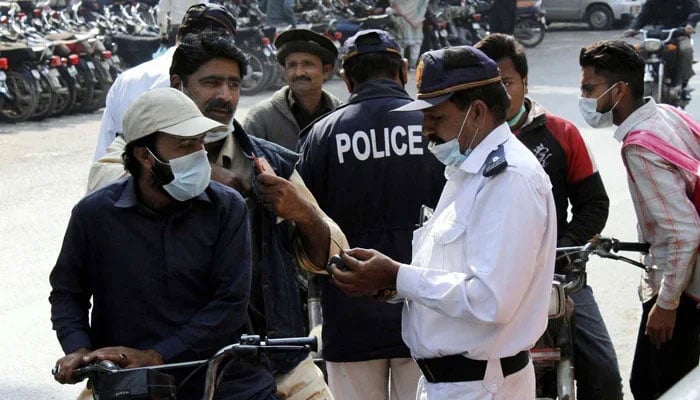 Traffic police staff issuing challan to people for violating traffic rules at Zainab Market in Karachi February 04, 2021. — PPI