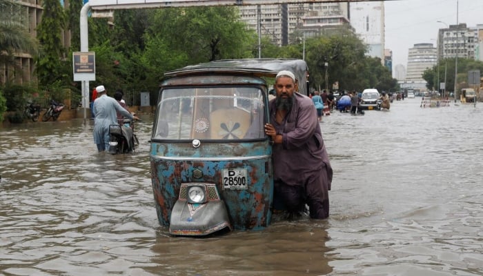 A man pushes his rickshaw through a flooded road during the monsoon season in Karachi, July 9, 2022. — Reuters