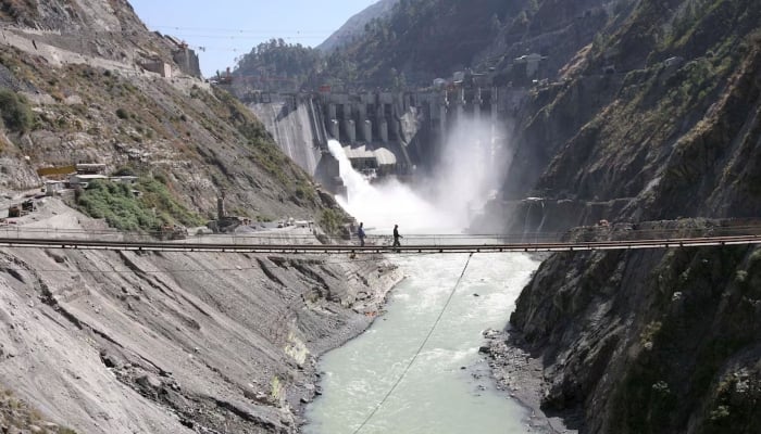 Labourers walk on a bridge near the 450-megawatt hydropower project located at Baglihar Dam on the Chenab river which flows from IIOJK into Pakistan, at Chanderkote, about 145 km (90 miles) north of Jammu, October 10, 2008. — Reuters