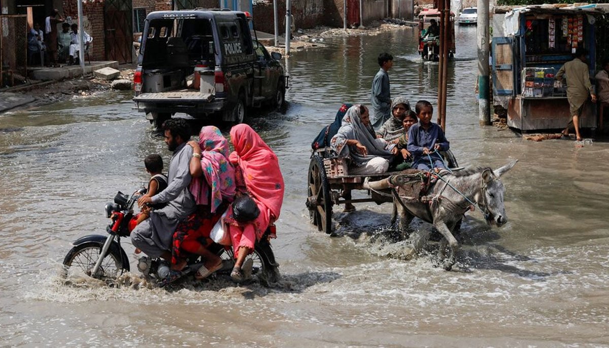 Commuters travel through rainwater, following rains and floods during the monsoon season in Jacobabad on August 30, 2022. — Reuters
